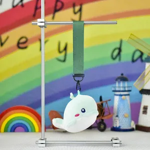 Detailed close-up of a cute whale plush toy keychain hanging on a deep green strap.