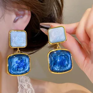 Nahaufnahme von eleganten Vintage-Ohrhängern mit blauem Sternenhimmel-Gradienten