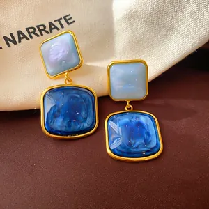 Detaillierte Nahaufnahme der blauen Vintage-Resin-Ohrhänger mit edlem Goldrahmen