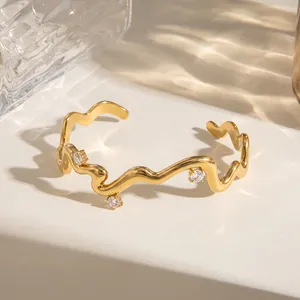 Detail eines wellenförmigen 18k vergoldeten Edelstahl-Armreifs mit Zirkoniasteinen