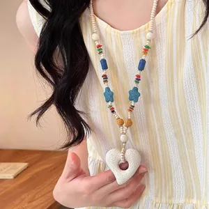 Detailed view of colorful volcanic stone beaded necklace with heart pendant on a model