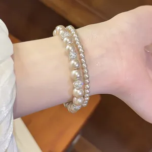 Detailansicht eines doppellagigen Perlenarmbands mit glitzernden Strasskugeln.