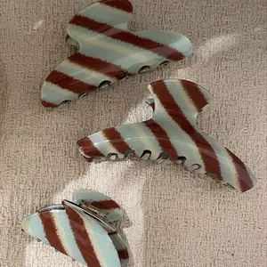 Elegante set van mintblauw en bruin gestreepte acetaat haarklemmen voor dames op stof.
