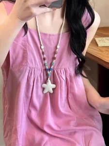 Detailed view of a colorful beaded necklace with a white starfish pendant on a model.
