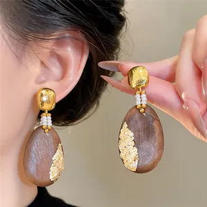 Detailansicht von Vintage-Holzohrringen in Ovalform mit Goldfolie und kleinen Perlen.