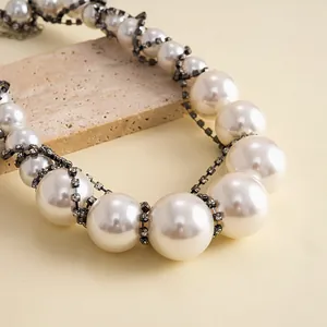 Detailansicht einer eleganten Vintage-Perlenkette mit funkelnden Strass-Elementen.