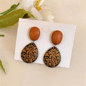 Detailansicht von Vintage-Ohrringen aus Holz mit filigranen schwarzen Blumenmustern