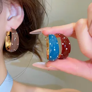 Vue détaillée de boucles d'oreilles créoles vintage à pois en émail coloré.