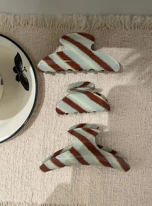 Elegante haarclips van acetaat met mintblauwe en bruine strepen in drie maten op getextureerde stof