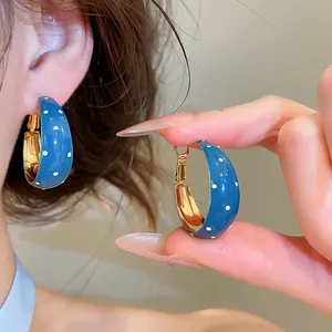 Détail de boucles d'oreilles créoles vintage en émail bleu avec motif à pois élégant