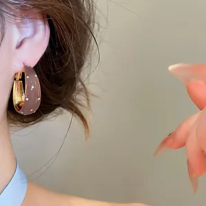 Gros plan de boucles d'oreilles créoles marron à pois rétro portées par un mannequin.