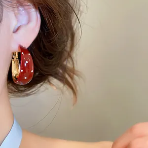 Gros plan de créole rétro en émail rouge à pois blancs portée sur l'oreille