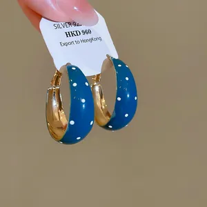 Gros plan de boucles d'oreilles créoles bleues à pois rétro avec intérieur doré élégant