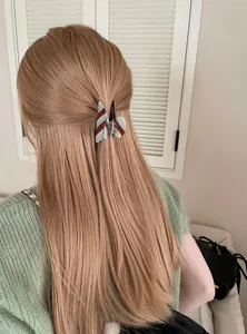 Detailweergave van een gestreepte blauw-bruine acetaat haarklem in een half opgestoken haar