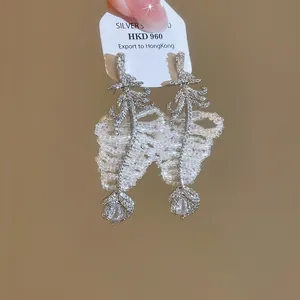 Vue détaillée des boucles d'oreilles feuilles en zircon avec franges de perles blanches