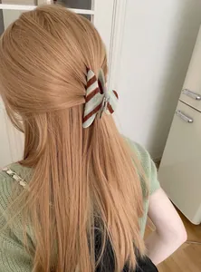 Close-up van een gestreepte acetaat haarklem gestyled in lang golvend blond haar