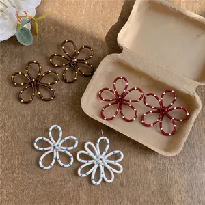Boucles d'oreilles fleurs à pois faites main en marron, rouge et blanc sur table en bois
