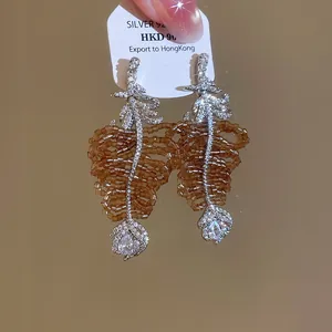 Gros plan d'élégantes boucles d'oreilles en zircon en forme de feuille avec perles.