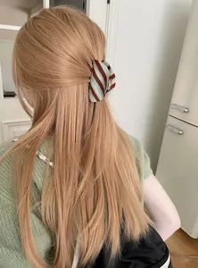 Gedetailleerd zicht op de mintblauwe en bruin gestreepte acetaat haarklem in blond haar