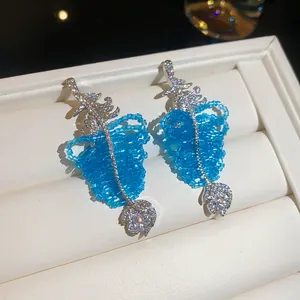 Détail de boucles d'oreilles de luxe en perles bleues avec feuilles et oxydes de zirconium.