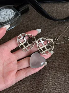 Détail d'un collier médaillon en forme de cœur argenté avec insert en acrylique gris amovible.