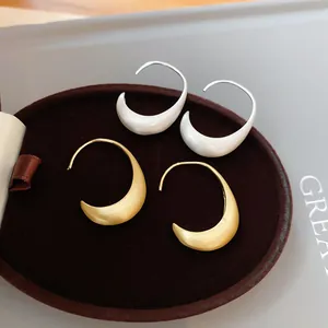 Macro detail showing the brushed texture of minimalist crescent moon earrings in gold and silver.