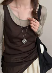 Détail d'un collier cœur en acrylique de style français avec strass porté par un mannequin