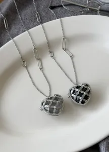 Vue détaillée de colliers en acrylique en forme de cœur avec cages argentées et diamants