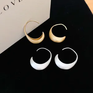 Detailed view of brushed metal arc earrings in gold and silver finishes