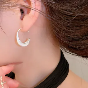 High-quality detailed view of matte brushed silver crescent moon hoop earrings on model