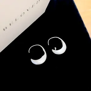 Detailed view of silver crescent hoop earrings with brushed metal finish on black velvet