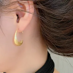 Detailed macro view of elegant golden brushed metal hoop earring on model's ear