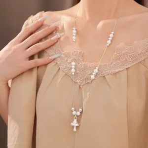 Elegante lange Halskette mit weißen Perlen und einem silbernen Pilzanhänger an einem Model.