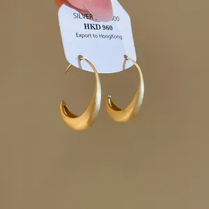 Close-up of gold minimalist hoop earrings with elegant brushed metal texture finish.