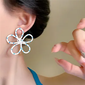 Eleganti orecchini a lobo a fiore bianco con pois blu indossati da una modella asiatica