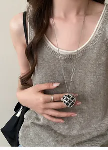 Détail d'un long collier français avec pendentif cœur en strass sur un mannequin.