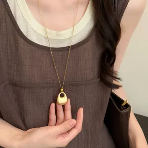 Detailweergave van een vintage gouden hanger ketting gecombineerd met een bruine plooijurk.