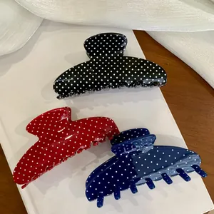 Close-up of three large polka dot hair claw clips in black, red, and blue colors