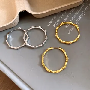 Close-up of gold and silver bamboo joint hoop earrings with sparkling rhinestones