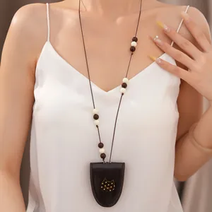 Elegante Lederband-Halskette mit Perlen und Katzenanhänger, getragen von einem Modell.