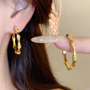 Detailed view of gold bamboo section hoop earrings with inlaid sparkling small diamonds