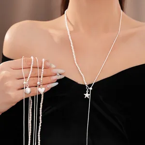 Elegante collana asimmetrica argentata con perle e ciondoli a stella su una modella