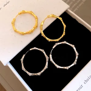 Detailed view of gold and silver bamboo joint hoop earrings with sparkly rhinestone accents.