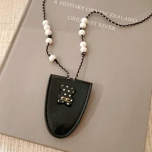 Nahaufnahme des schwarzen Brillenetuis aus Leder mit süßem gepunktetem Bärenanhänger.