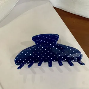 Detailed view of a stylish large blue hair claw clip featuring classic white polka dots