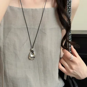 Detailopname van een Franse vintage metalen hanger ketting gedragen door een model.