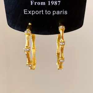 Close-up detail view of elegant gold bamboo joint hoop earrings with sparkling rhinestones