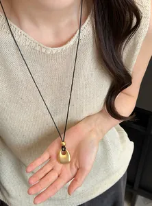 Gedetailleerd overzicht van een vintage matgouden druppelhanger aan een lang koord