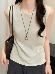 Detailopname van een gouden geplooide hanger ketting op een beige gebreide top.