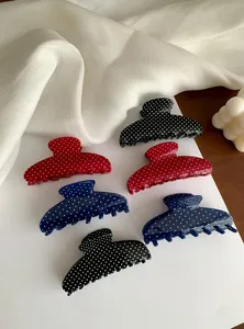 Macro detail view of large polka dot hair claw clips in black, red and blue colors.
